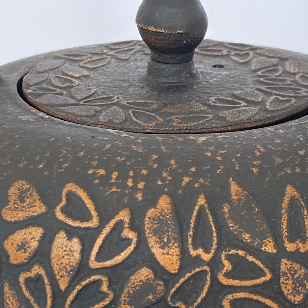 Decorative metal object with heart patterns on a white background