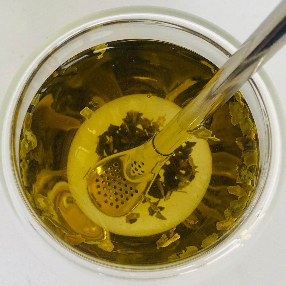 Bombilla Tea infuser in a glass of tea on a white background