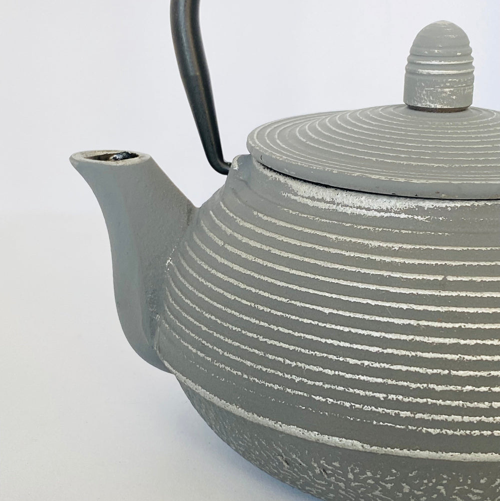 Gray teapot with ribbed design on a white background