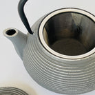 Gray textured teapot with black handle on a white background