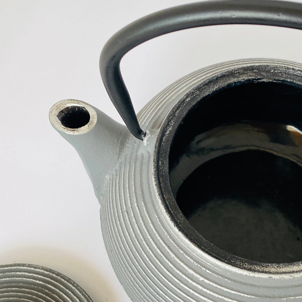 Close-up of a textured ceramic teapot with a black handle on a white background