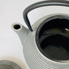 Close-up of a textured ceramic teapot with a black handle on a white background